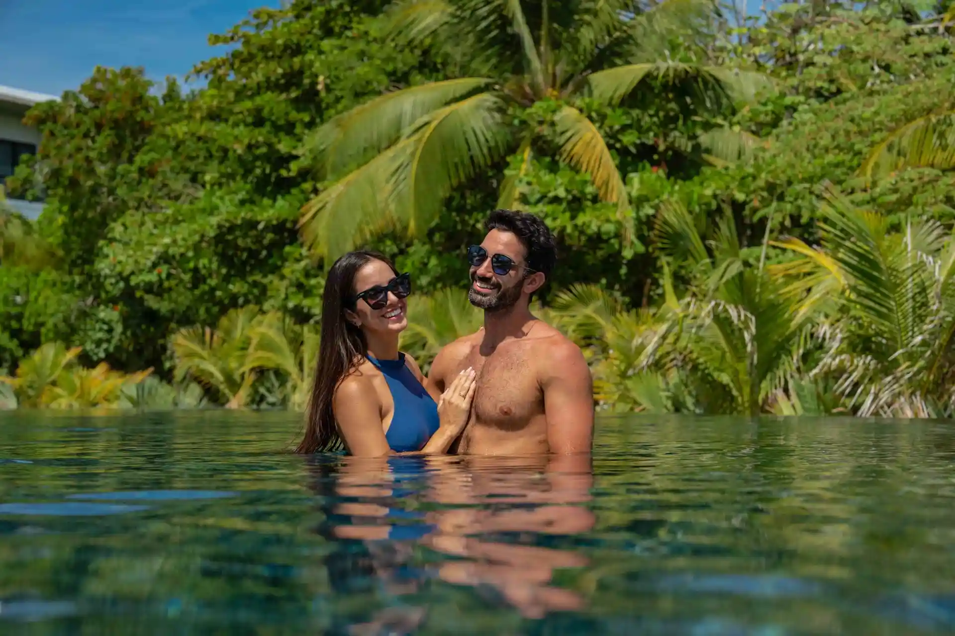 Couple surrounded by lush vegetation enjoying the pool at Conrad Tulum Riviera Maya hotel