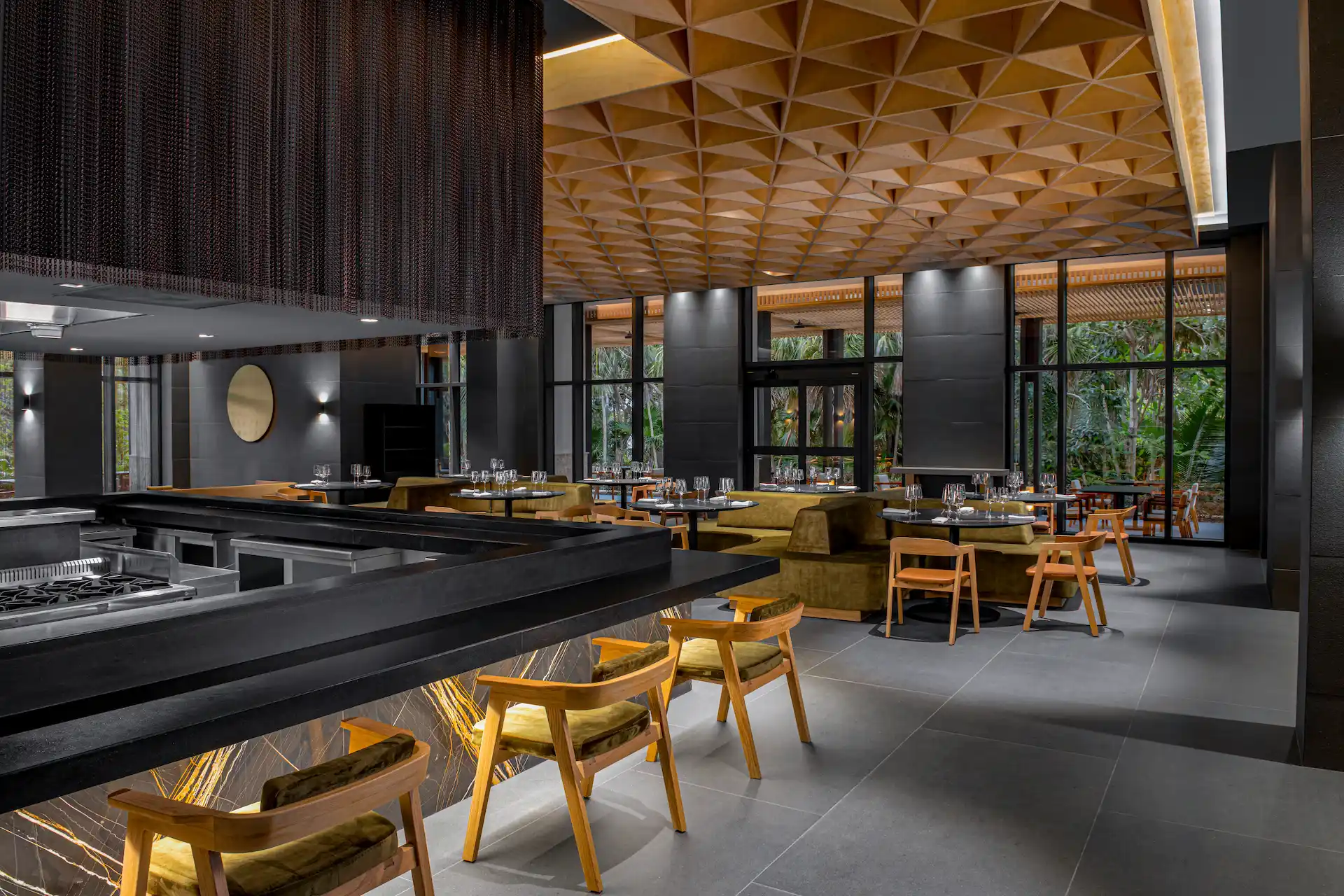 View of the bar at Autor restaurant in Conrad Tulum Riviera Maya, featuring a sleek design, stylish seating, and a well-stocked display