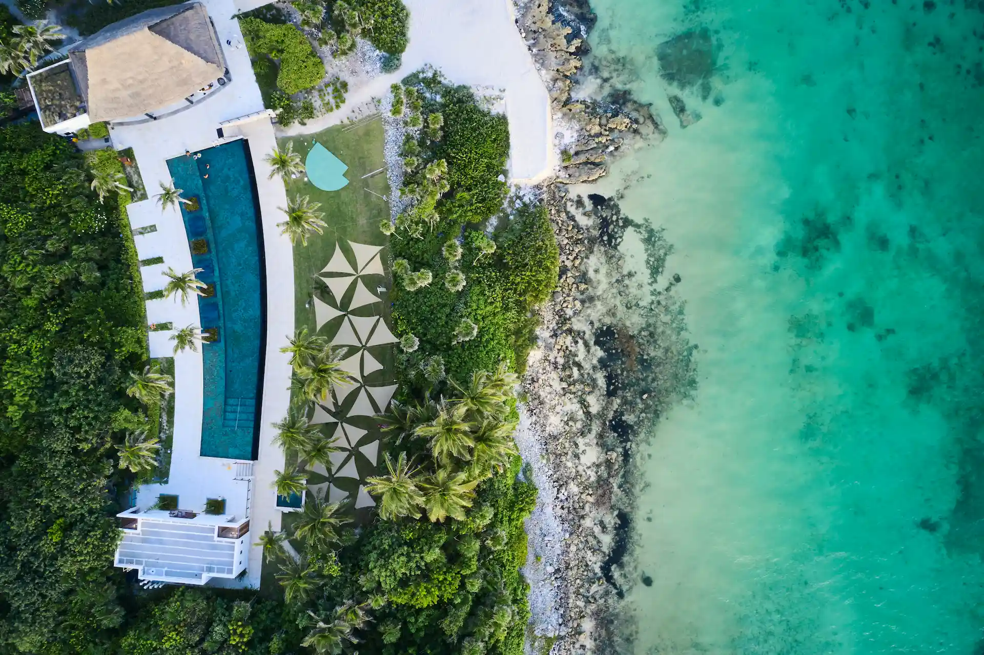 Drone aerial view of the pool and private beach at Conrad Tulum, showcasing the resort's luxury and breathtaking coastal scenery