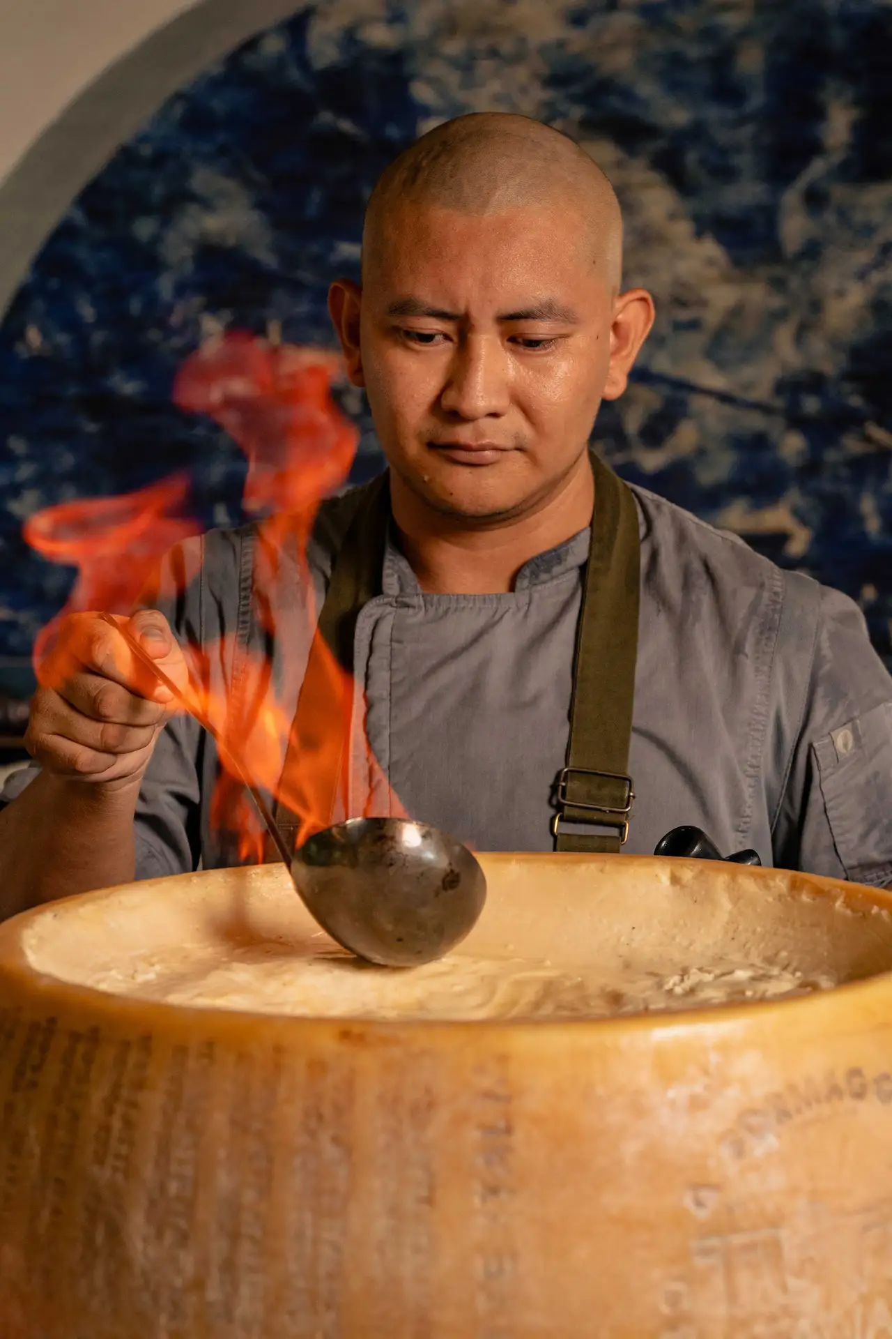 Chef cooking pasta in a cheese wheel at Maratea restaurant, Conrad Tulum Riviera Maya hotel