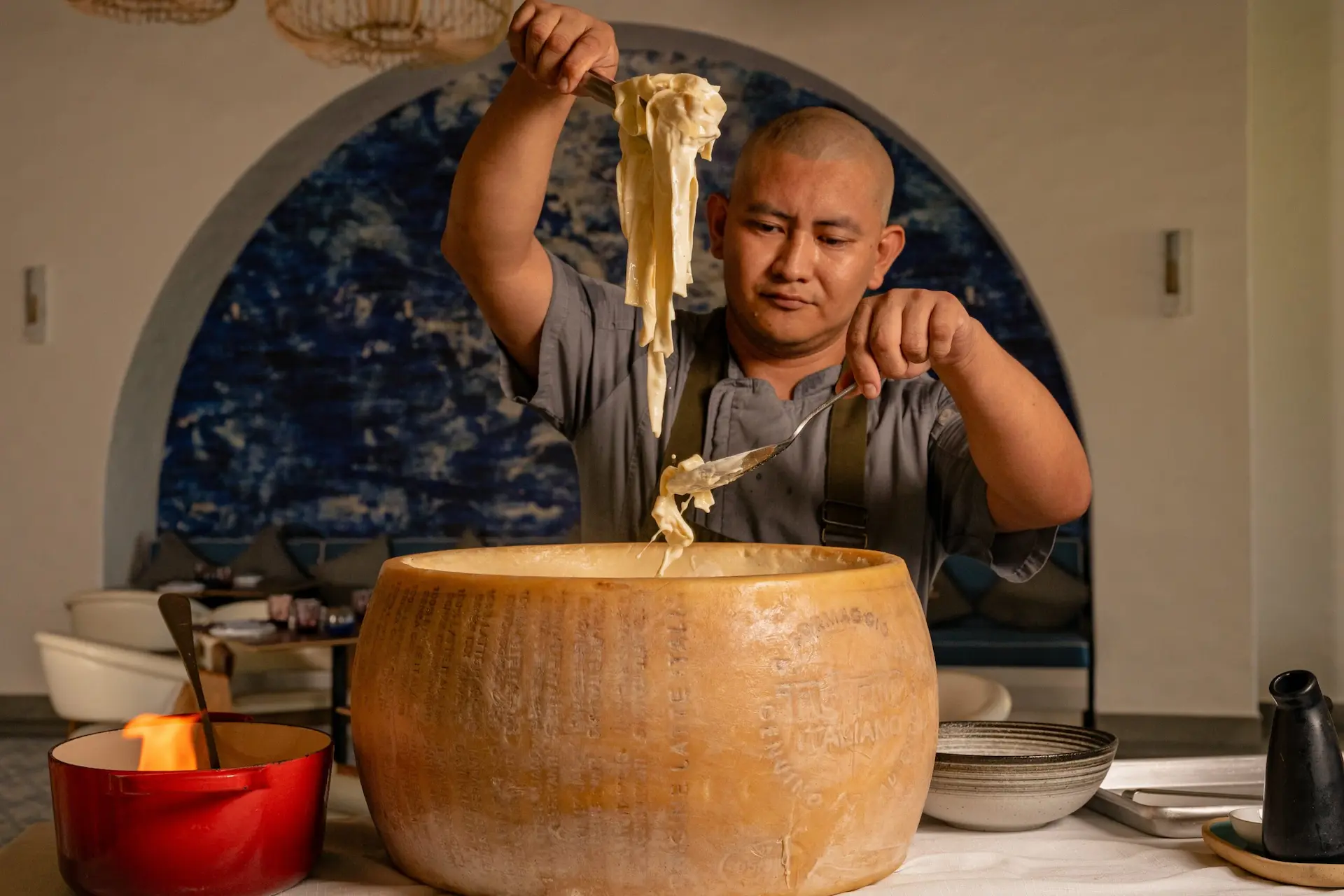 Chef serving pasta inside a cheese wheel at Maratea restaurant