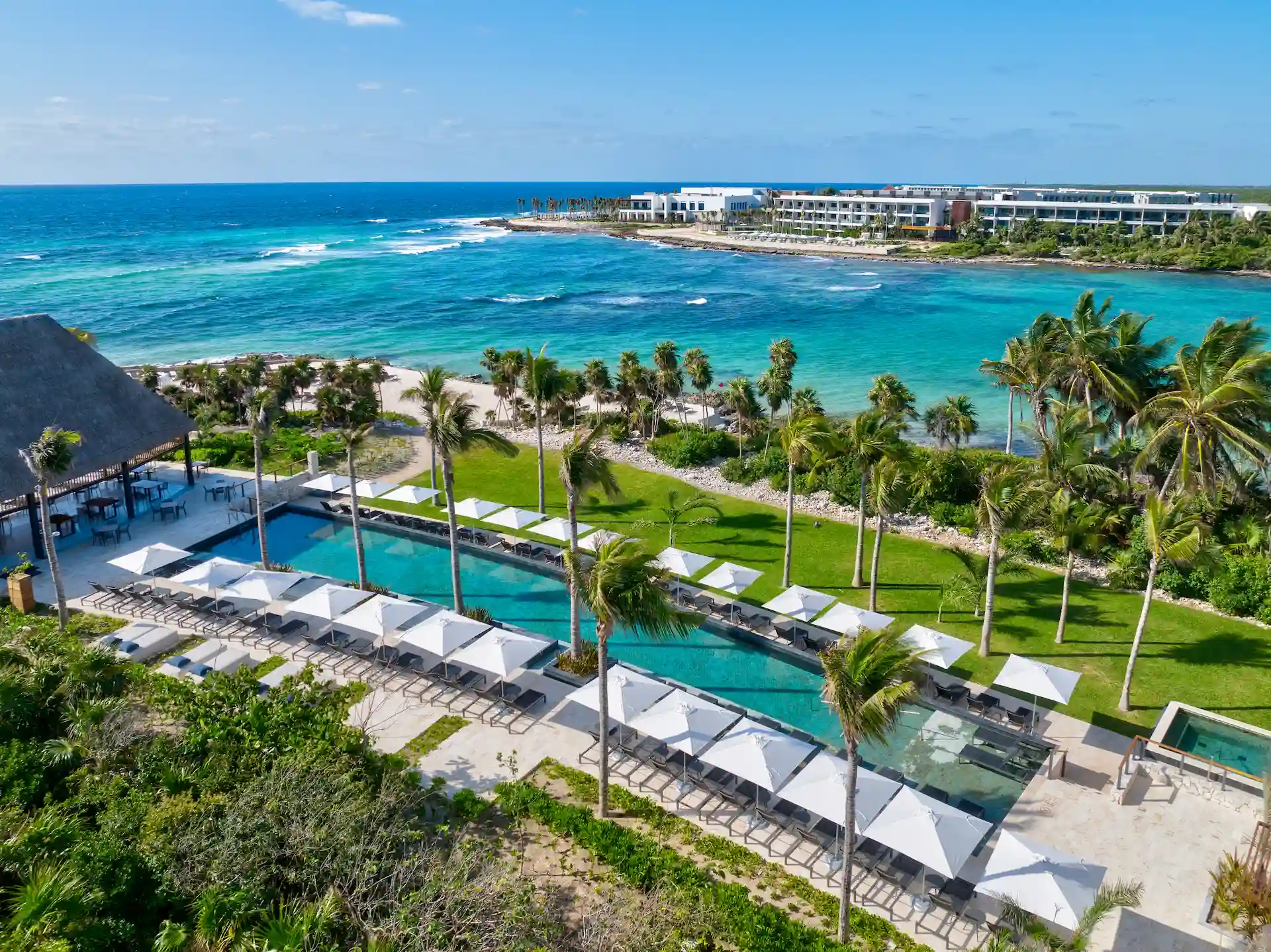 Green areas surrounding the hotel pool with stunning ocean views at Conrad Tulum Riviera Maya