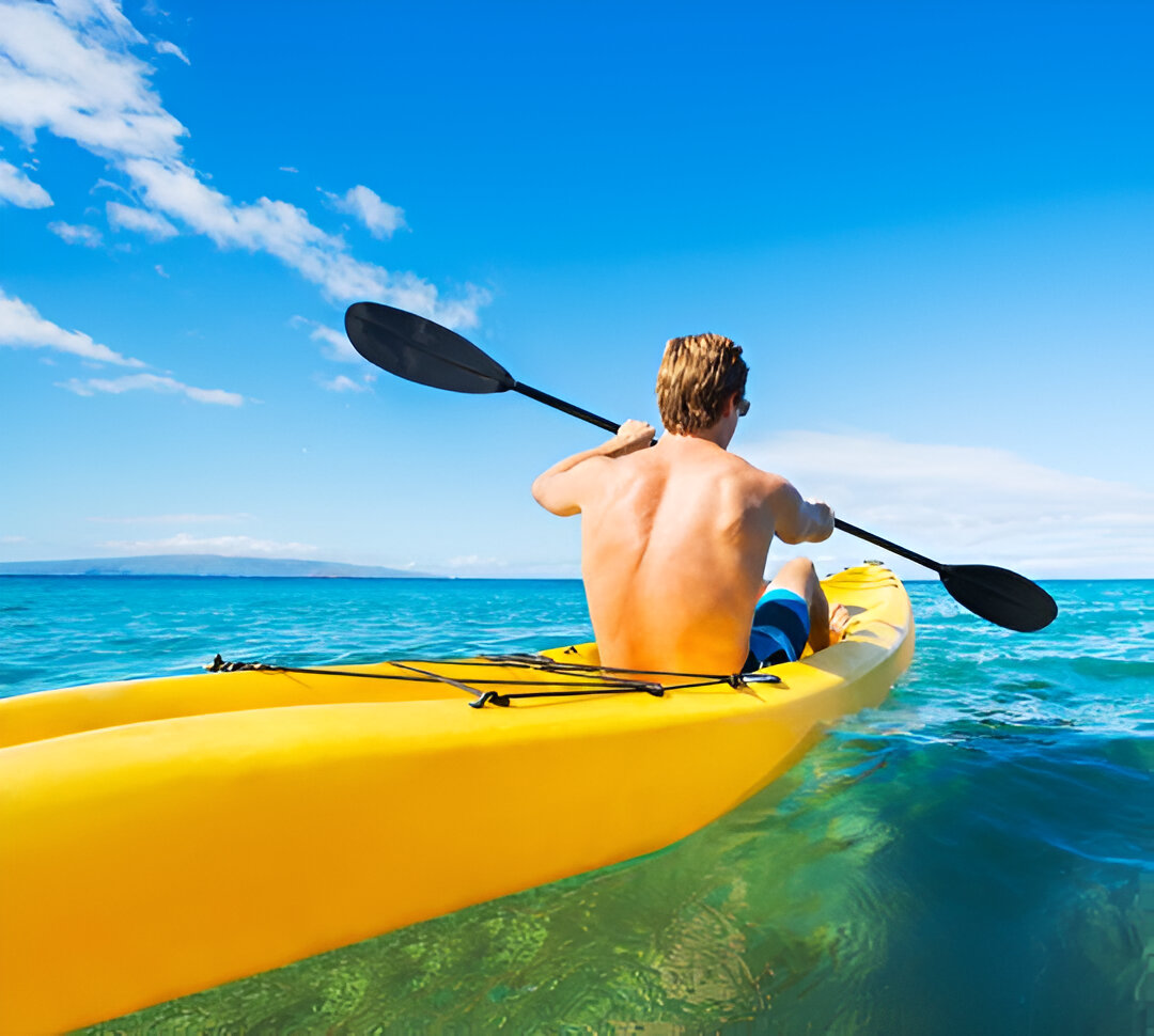 Man paddling a kayak through calm waters near Conrad Tulum, enjoying a scenic and peaceful adventure