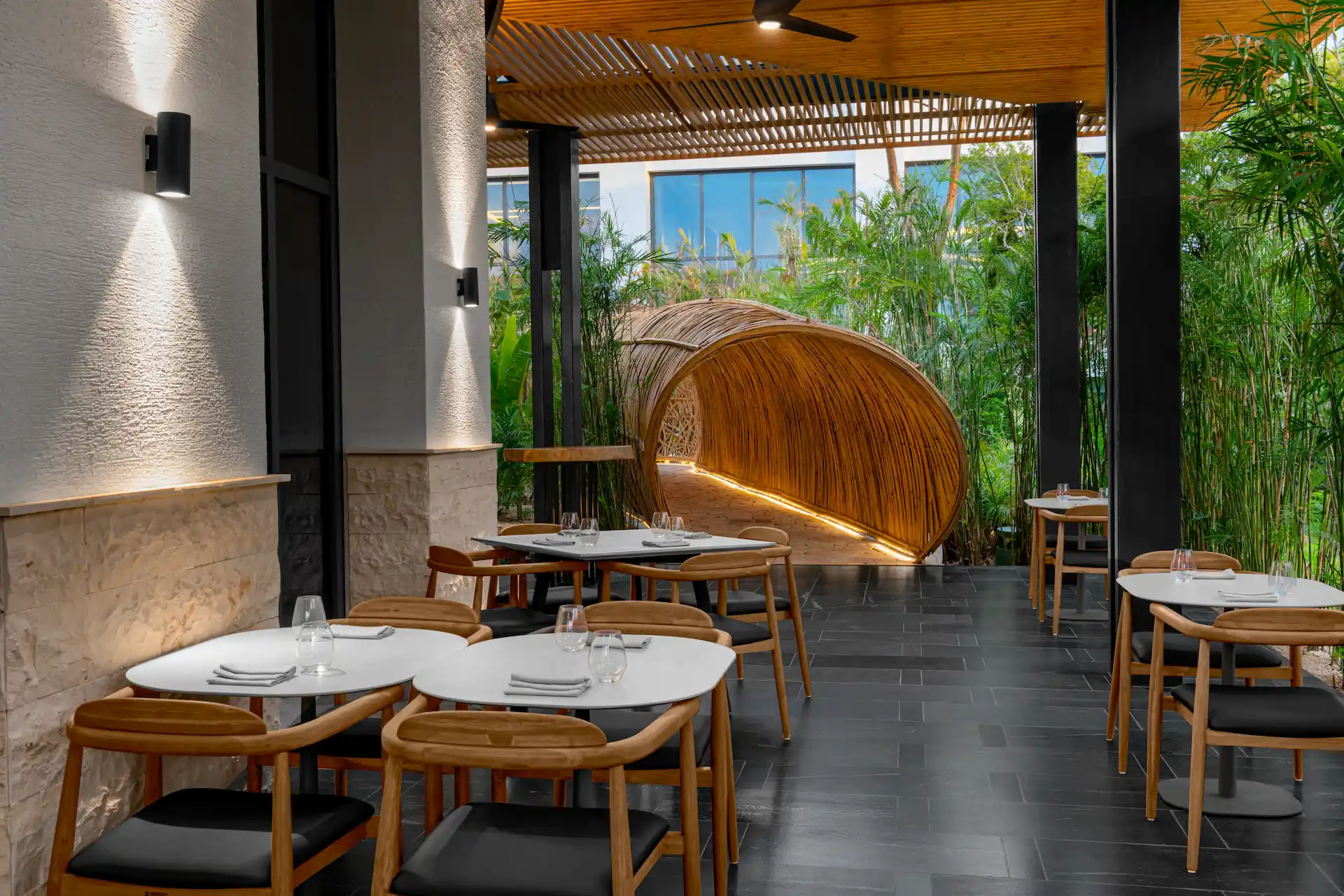 Interior of Kengai restaurant with elegant decor and cozy seating, featuring an entrance tunnel made of tropical reeds