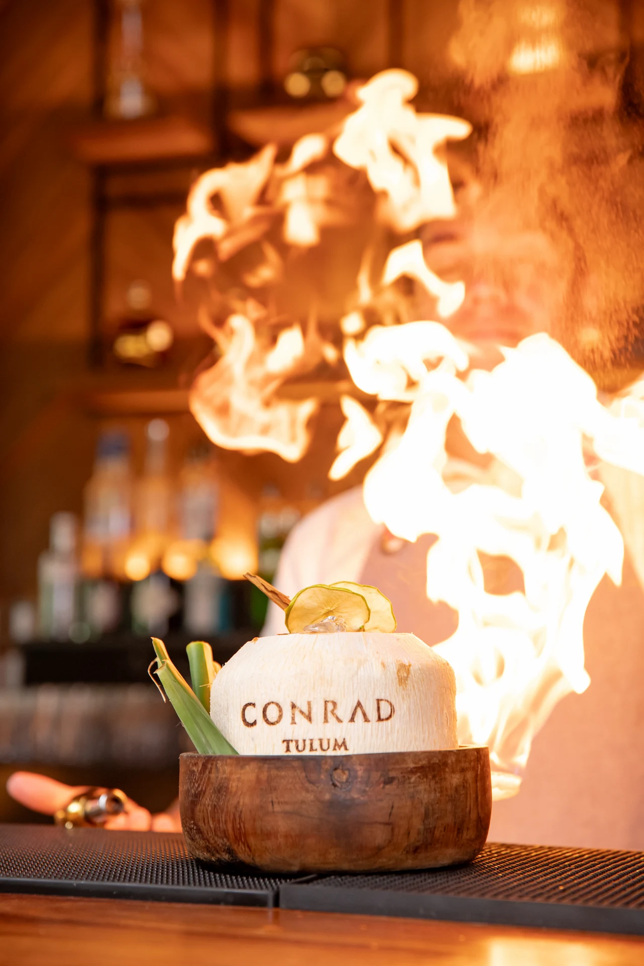 Cocktail served in a coconut with a fire backdrop at Chaak Bar