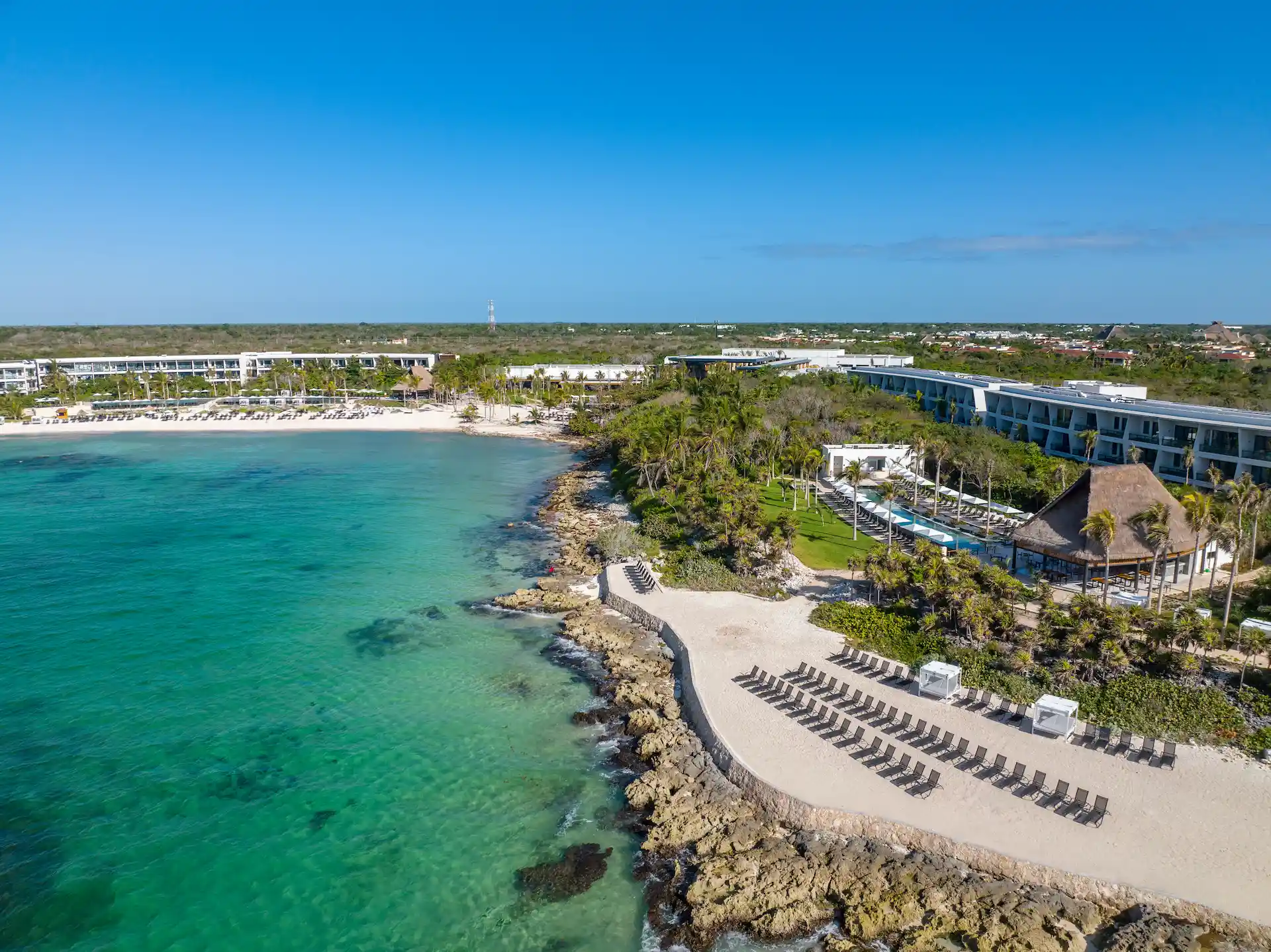 Aerial view of Conrad Tulum Riviera Maya showcasing the pool area and beachfront with clear turquoise waters.