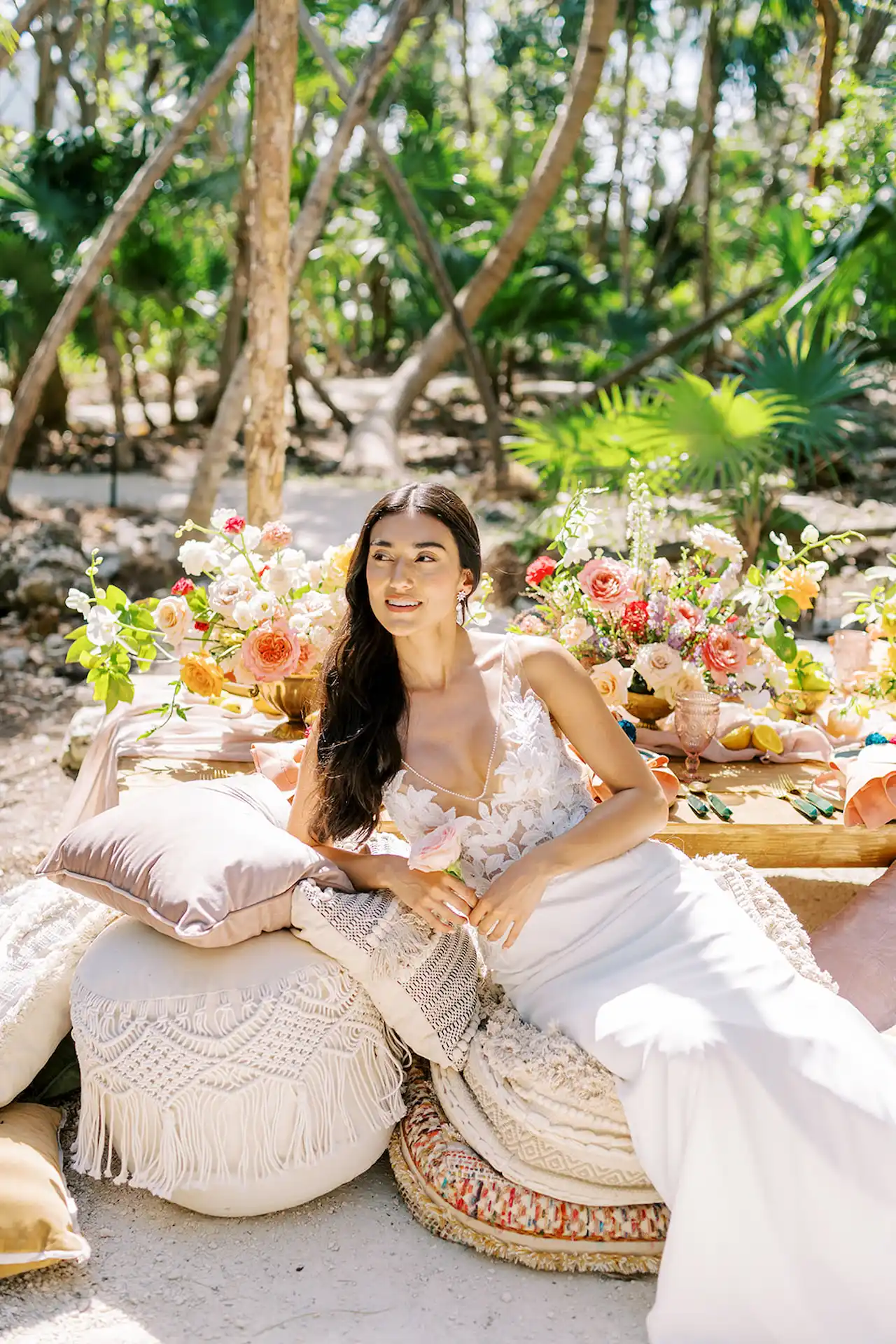 Bride elegantly posing on a stylish seat, showcasing her wedding gown and joyful expression on her special day at Conrad Tulum