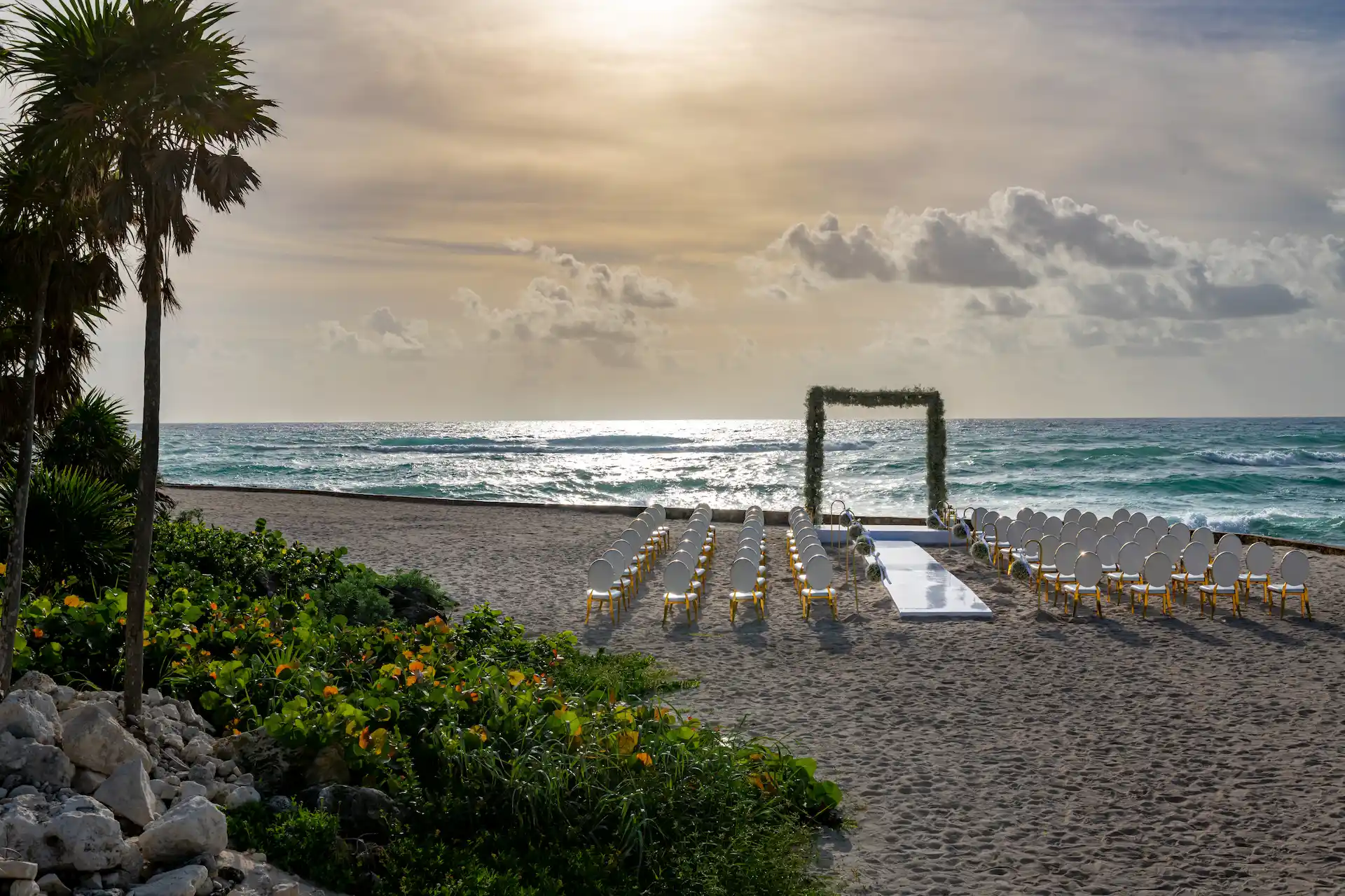 "Chairs and beautifully decorated altar prepared for a beach wedding on the private beach of Conrad Tulum