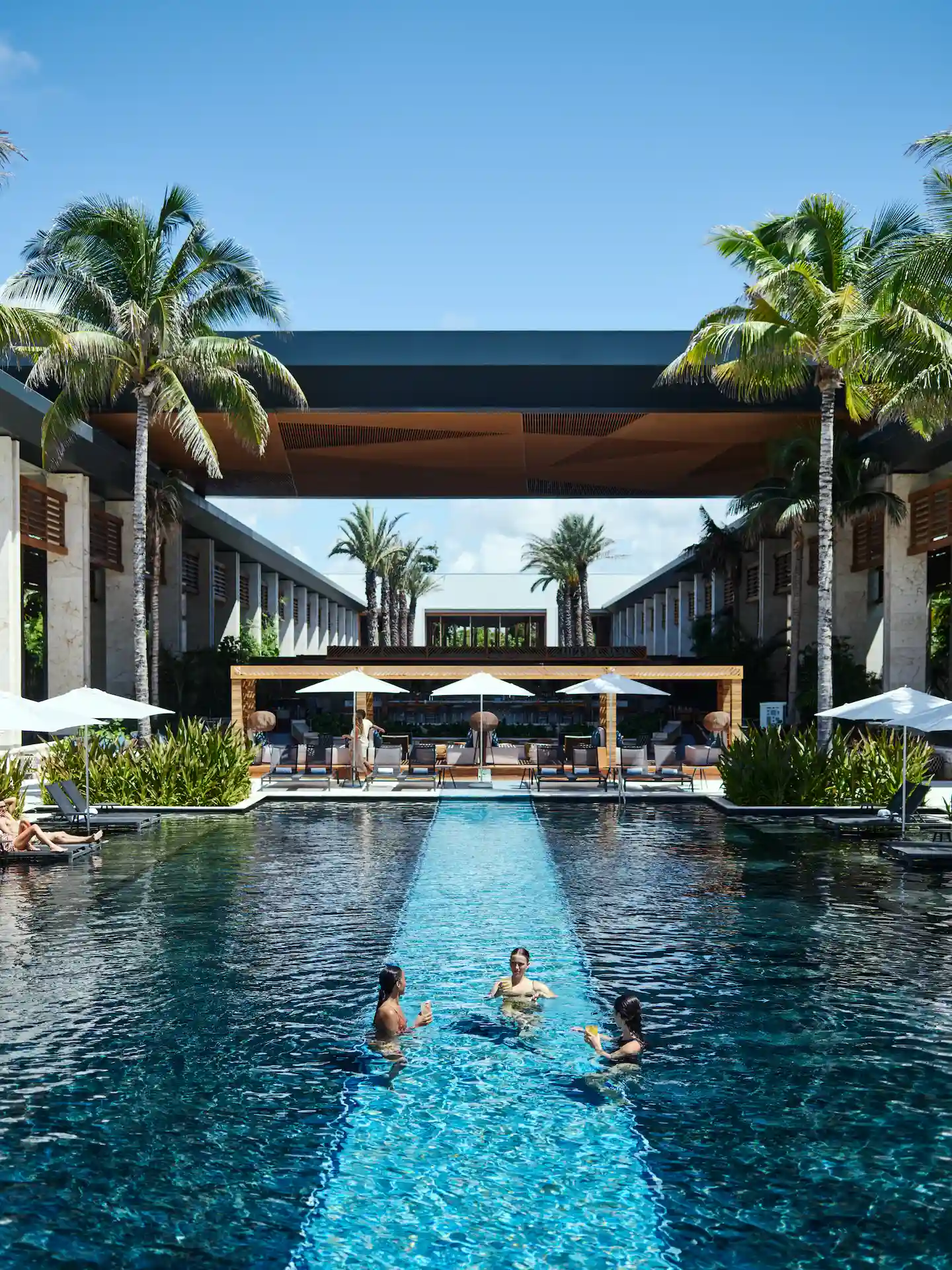 Three friends enjoying themselves in the main pool of Conrad Tulum Riviera Maya