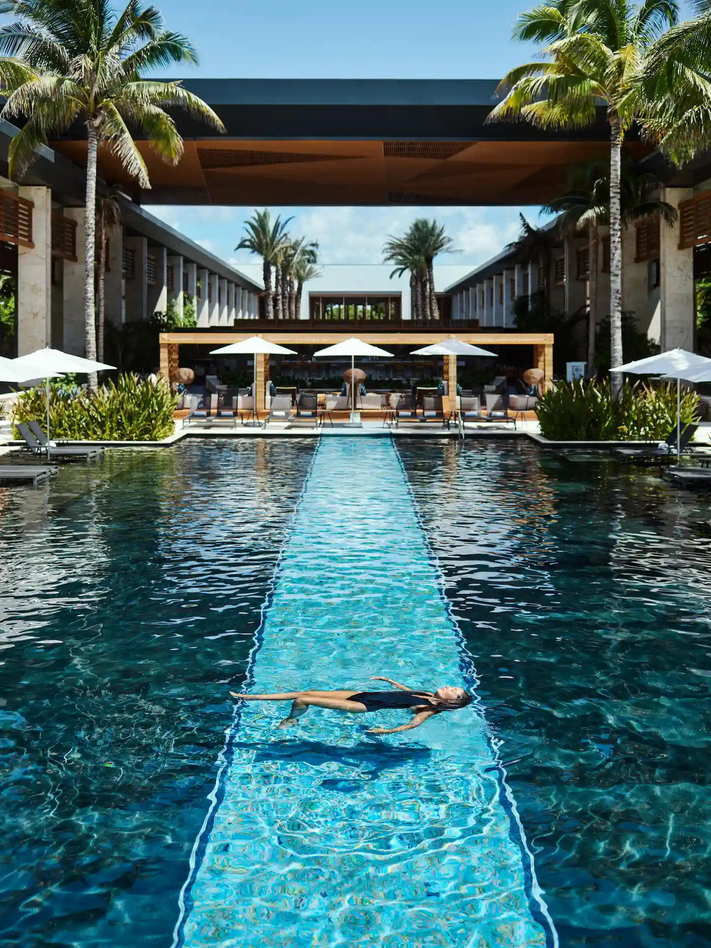 Woman swimming in the pool at Conrad Tulum Riviera Maya, surrounded by tropical greenery and serene luxury