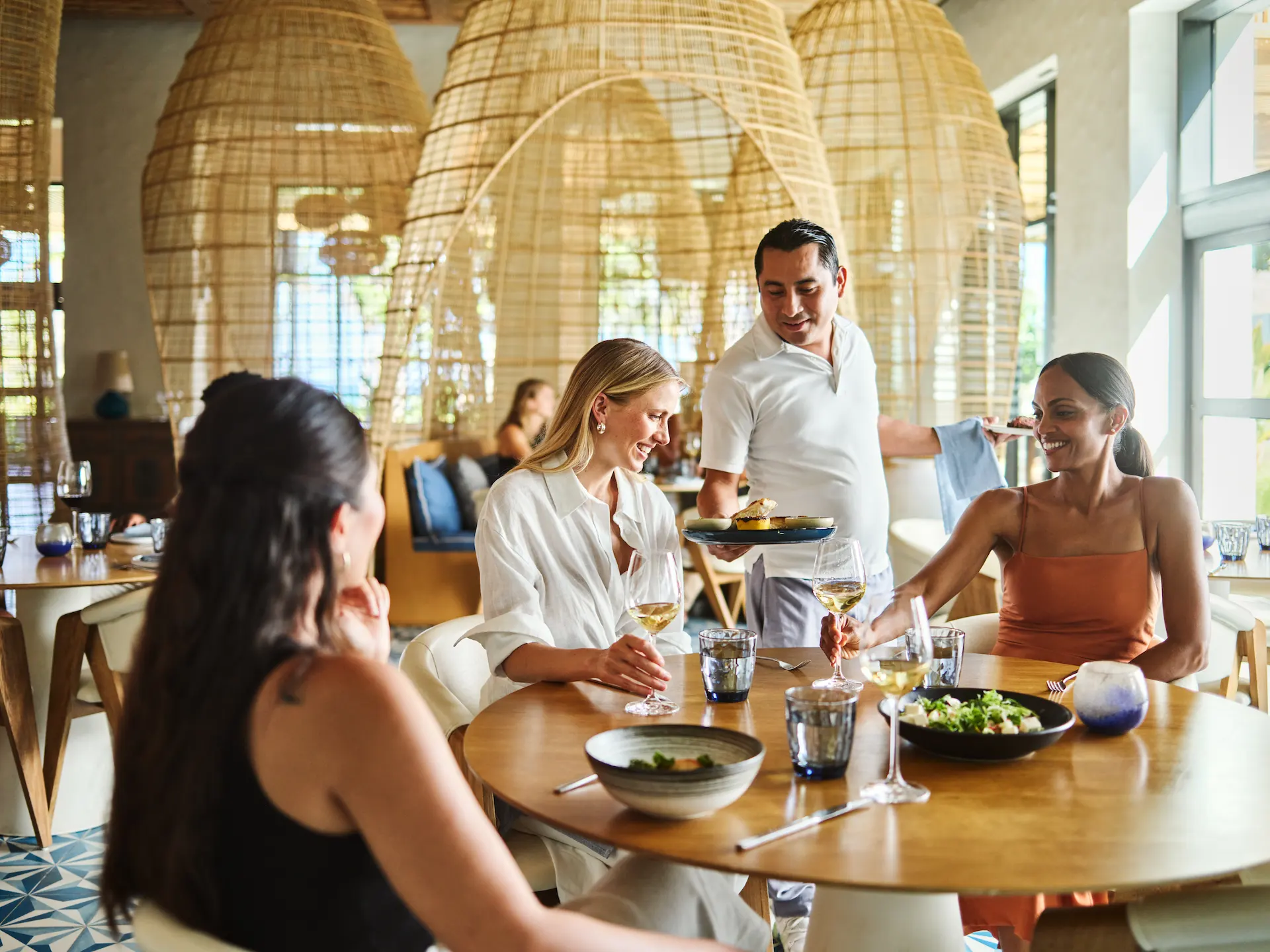 Waiter serving a delightful meal to guests at the Maratea restaurant in Conrad Tulum