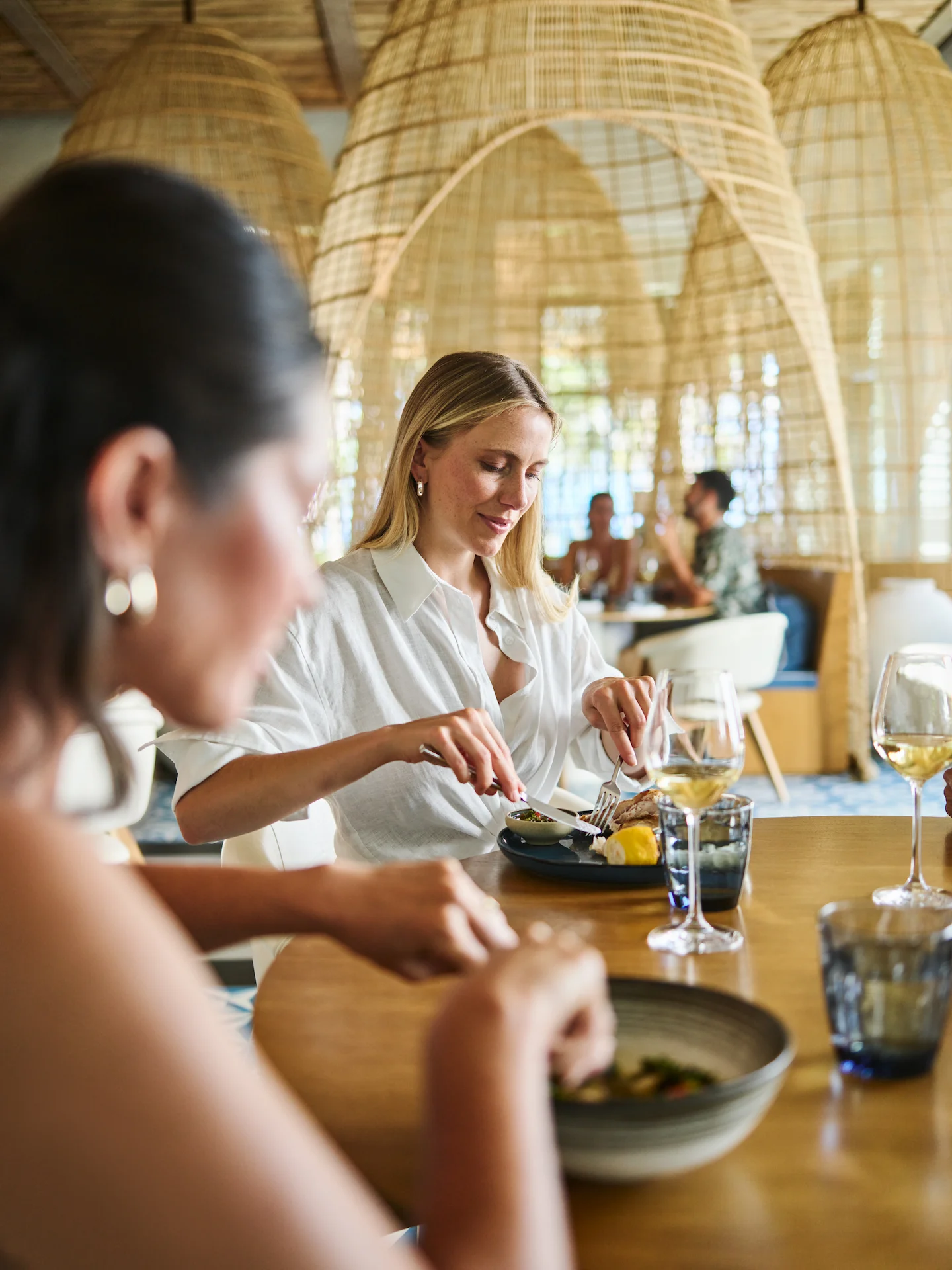 Two women enjoying a meal at Conrad Tulum, sharing delicious dishes in a delightful setting