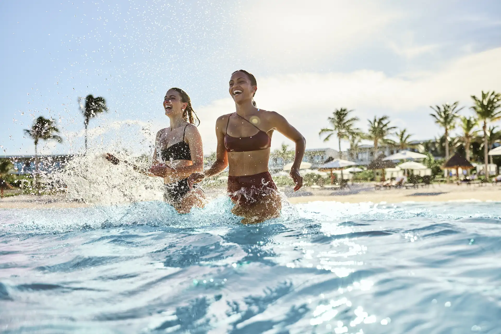 Two friends smiling and enjoying themselves while swimming in the clear waters of the private beach at Conrad Tulum