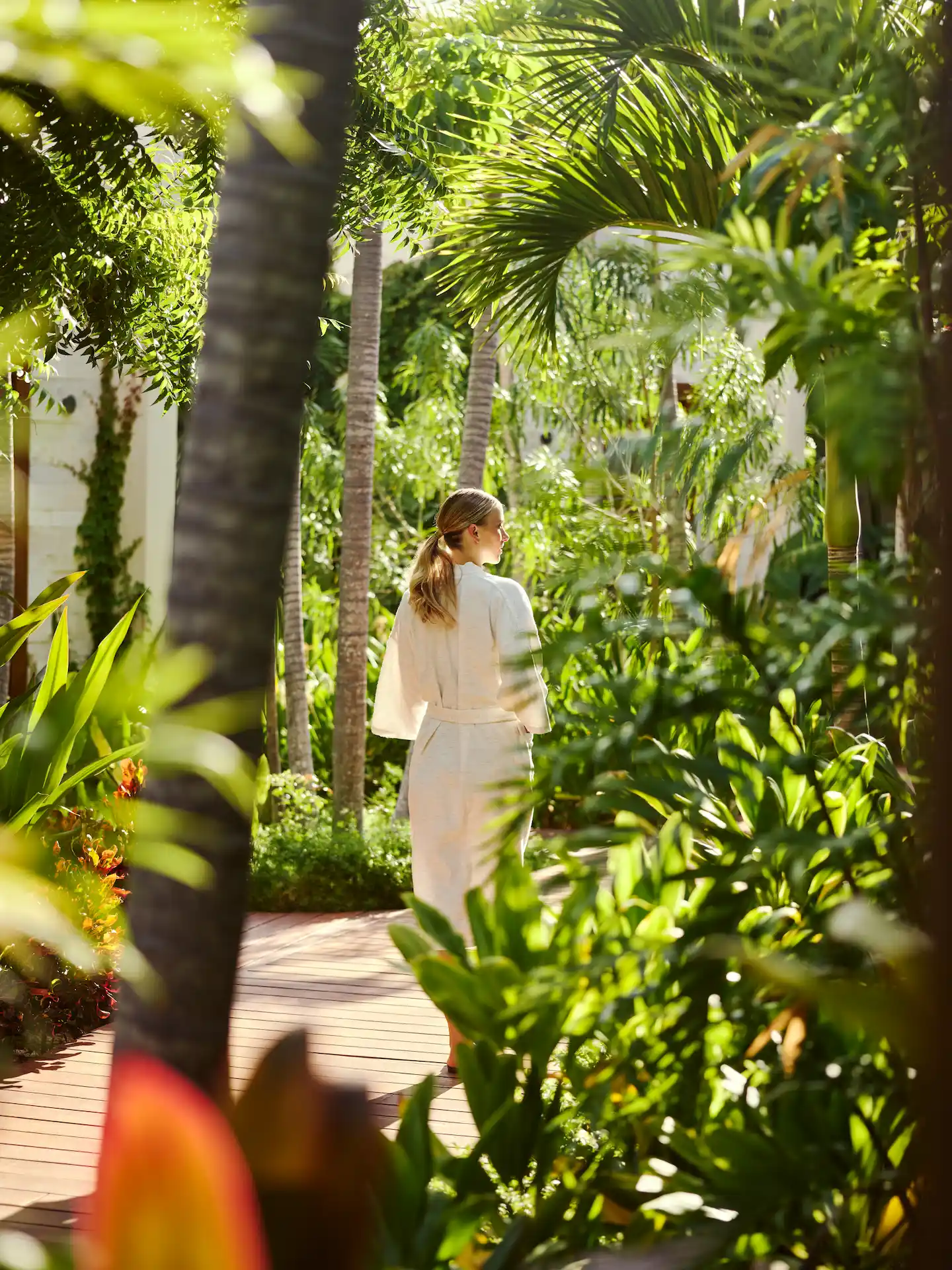 Woman wearing a bathrobe, strolling through the hotel garden, surrounded by lush vegetation