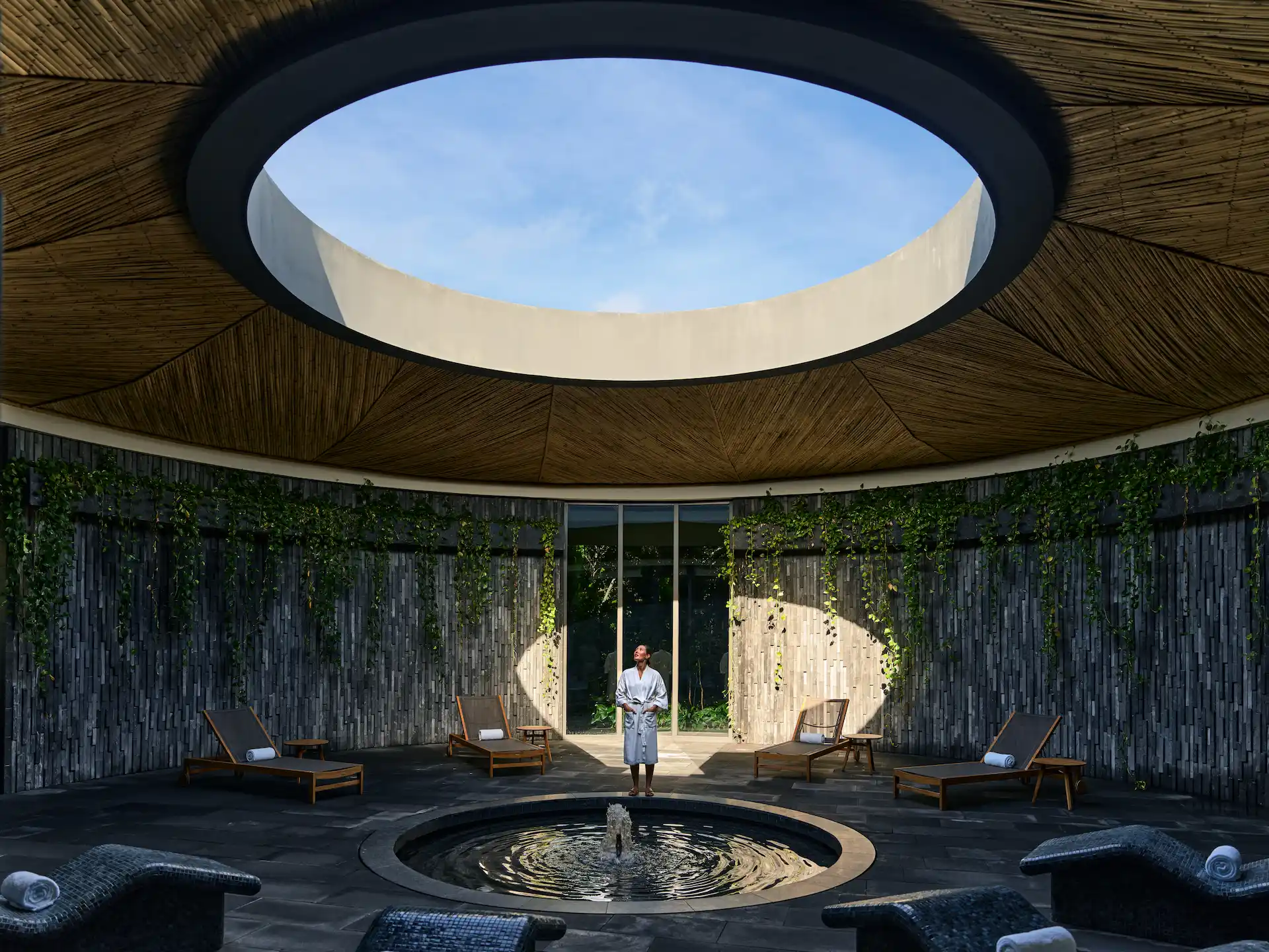 Woman looking up at a skylight in the spa at Conrad Tulum, enjoying the serene atmosphere of the cenote