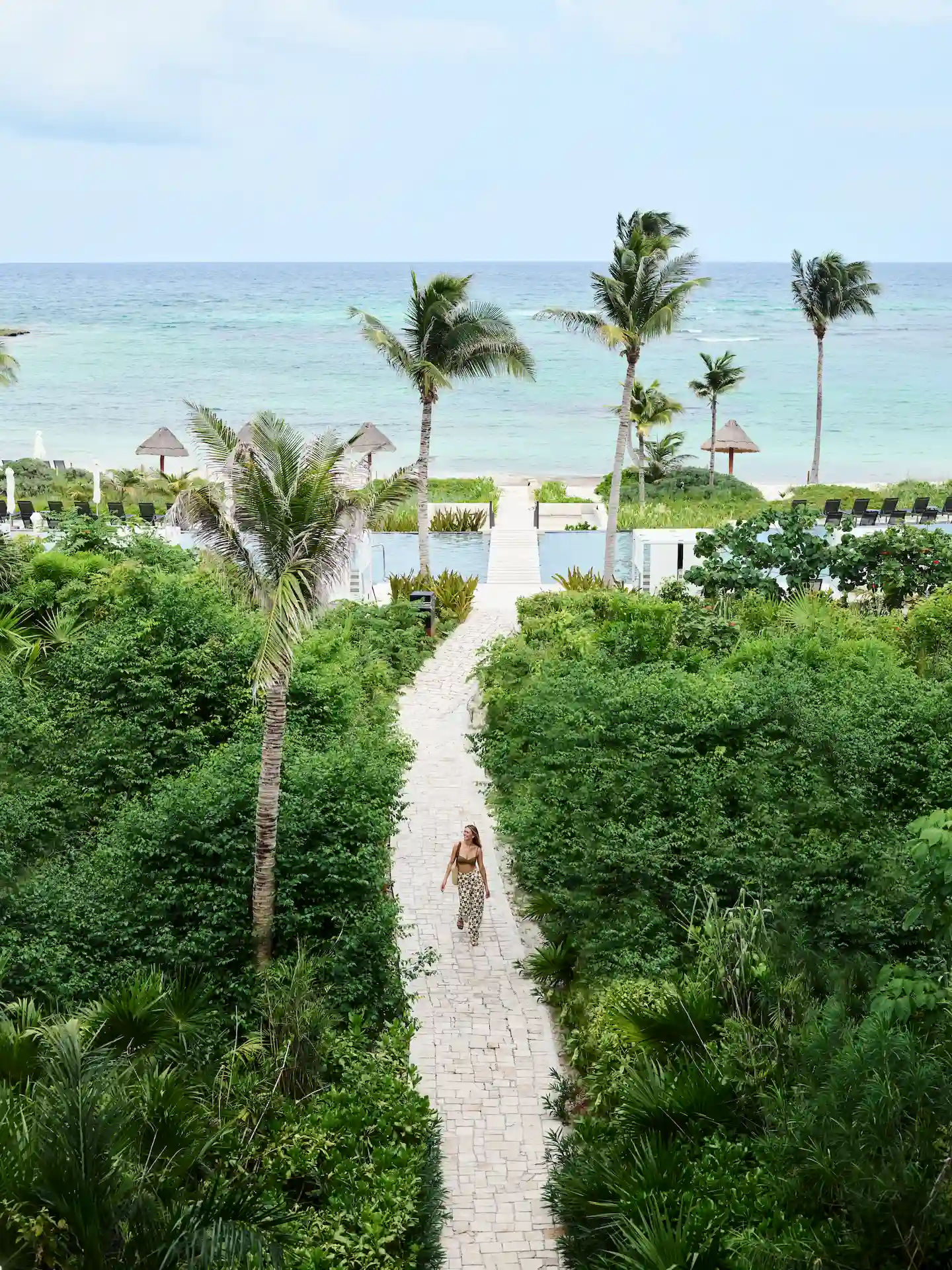 Woman walking along a beach path at the hotel, surrounded by lush vegetation and enjoying the natural beauty