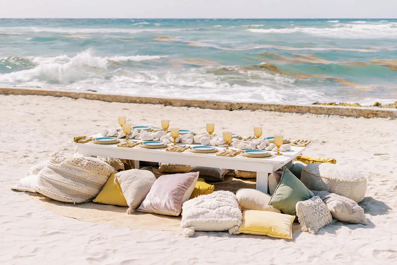 Dining table set up with cushions on the beach sand