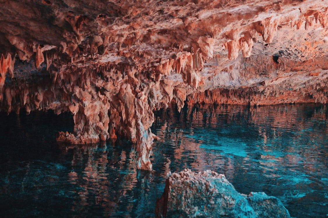 Interior of a cenote in Tulum featuring stunning stalactites and crystal-clear waters